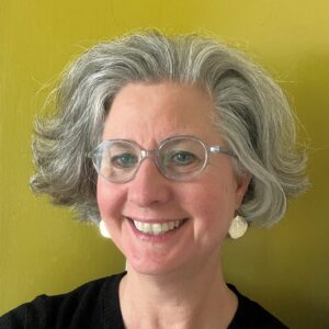 Close headshot of Lynn Barlow in front of a yellow wall