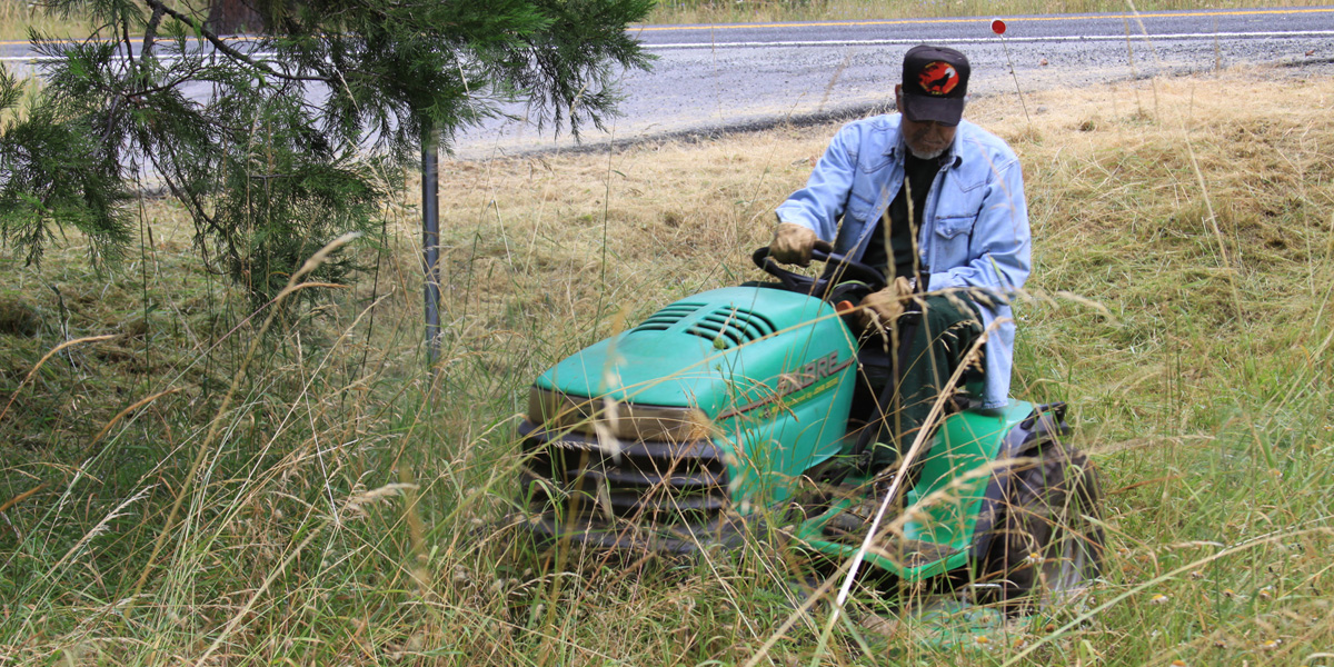 man on riding lawn mower cutting tall grass
