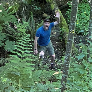 Person standing in forest waving at camera