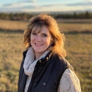 Lorrie Conway smiles on a field with a glowing sunset behind