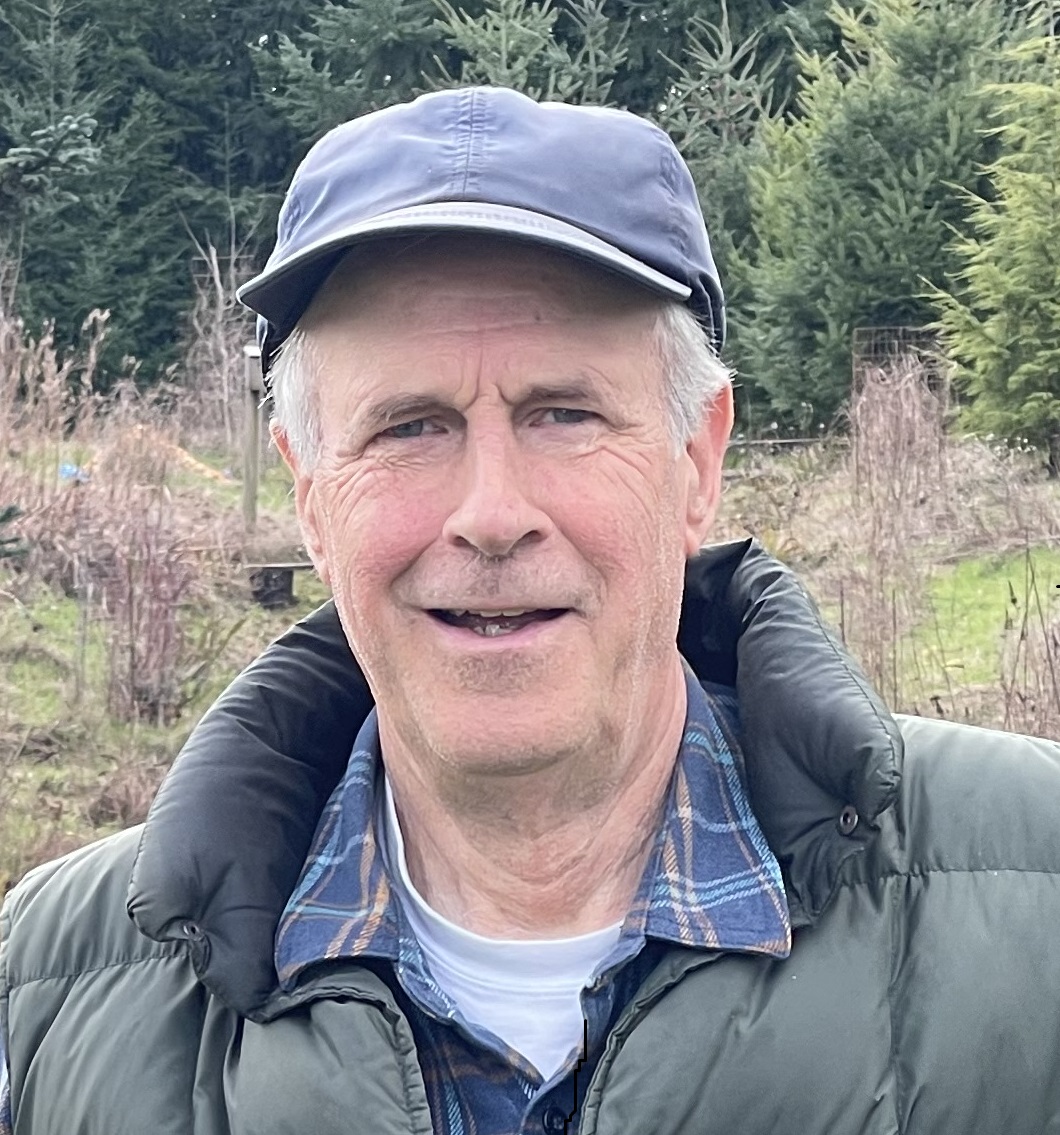 Kevin, a white man with white hair, a baseball cap, and a puffy jacket, smiles at the camera