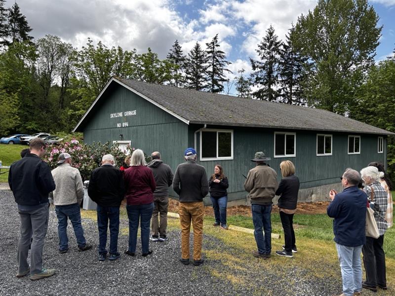 A large group of people stand in front of a blue building.