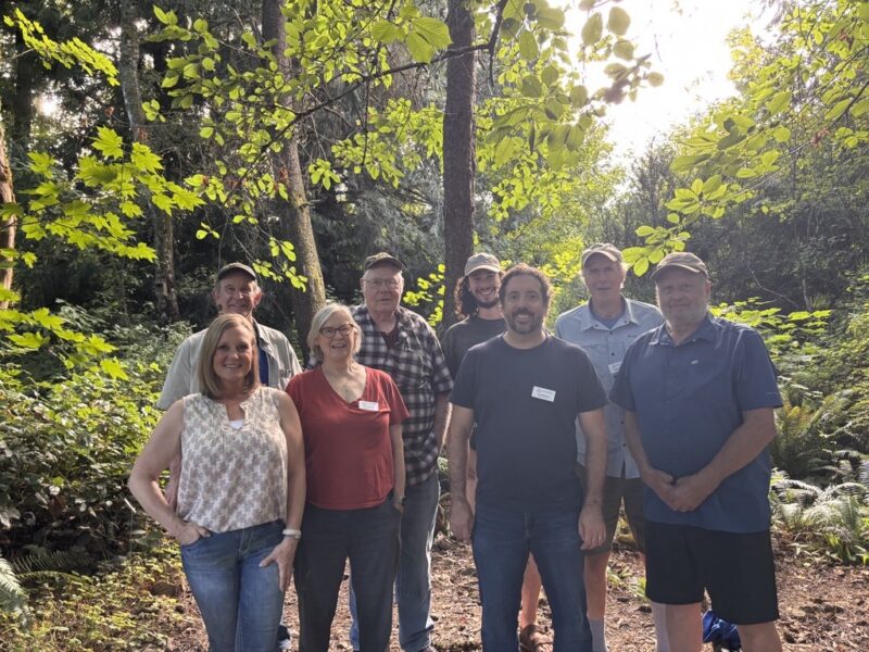 Group of 8 men and women from our board smiling in the woods.