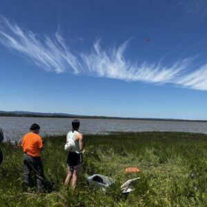 Three people look out over a lake.