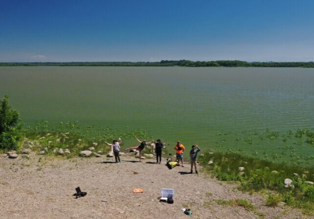 5 staff members standing on the shore of Sturgeon Lake, shot taken from a drone