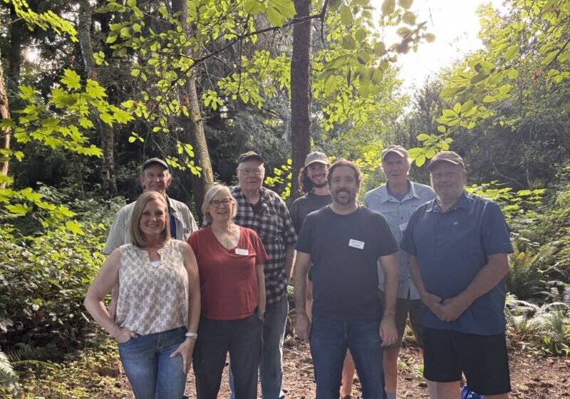 Group of 8 men and women from our board smiling in the woods.