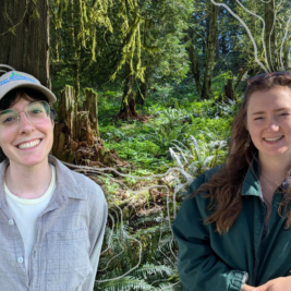 Two smiling women in front of a forested background