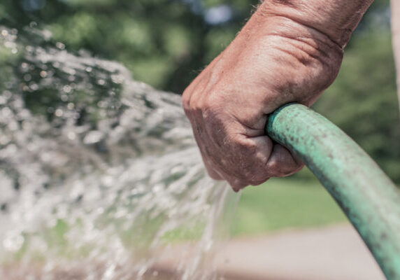hand holding a garden hose spraying water